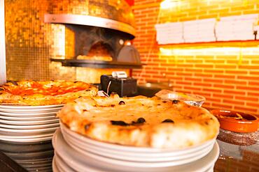 Artisan pizza oven. Freshly made pizza coming out of the oven, pizza hot and ready for customers