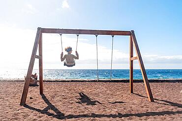 A woman on vacation swinging on a swing on the beach of the island of El Hierro. Canary Islands