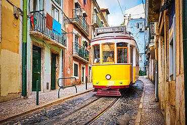 Famous vintage yellow tram 28 in the narrow streets of Alfama district in Lisbon, Portugal, symbol of Lisbon, famous popular travel destination and tourist attraction, Europe