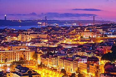 Night view of Lisbon famous view from Miradouro da Senhora do Monte tourist viewpoint of Alfama and Mauraria old city districts, 25th of April Bridge in the evening twilight. Lisbon, Portugal, Europe