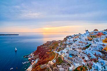 Famous greek iconic selfie spot tourist destination Oia village with traditional white houses and windmills in Santorini island on sunset in twilight, Greece, Europe