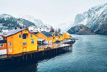 Panorama of Nusfjord authentic fishing village with yellow rorbu houses in Norwegian fjord in winter. Lofoten islands, Norway, Europe