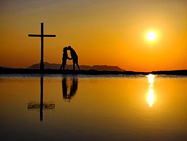 Couple kissing next to summit cross at sunset, silhouette, reflection in water, Trattberg, Bad Vigaun, Land Salzburg, Austria, Europe