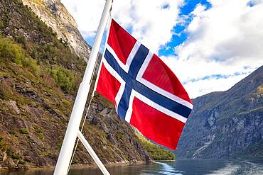 Norwegian flag in front of mountain panorama in Geirangerfjord near Geiranger, UNESCO World Heritage Site, Norway, Europe