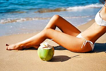 Beautiful woman relax on tropical sandy beach with coconut. Vacation concept, summer background