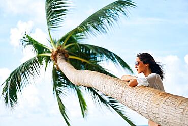 Dreaming beautiful woman relax on tropical beach with palm tree. Carefree concept