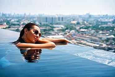 Young woman relax on the edge of the roof top swimming pool. Summer vacation concept