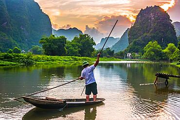 Fisherman on boat in Trang An, a scenic area near Ninh Binh, Vietnam inscribed as a UNESCO World Heritage Site in 2014