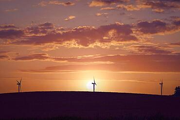 Windmill silhouettes on a hill in a beautiful sunset with dramatic sky