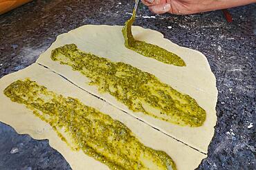 Swabian cuisine, preparing hearty party yeast plait, salty yeast plait, yeast pastry, filling yeast yeast dough with herb paste, pesto, raw dough, vegetarian, man's hand, worktop, teaspoon, typical Swabian reinterpreted, traditional cuisine, food photography, studio, Germany, Europe