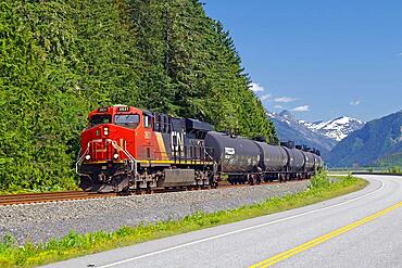 Locomotive and wagons of a long goods train next to a road, Prince Rupert, British Columbia, Canada, North America