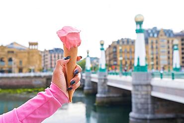 Eating strawberry ice cream on summer vacation in the city of San Sebastian next to the Urumea river. Spain