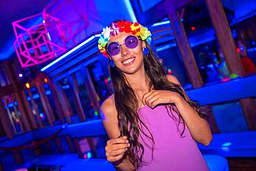 Brunette woman smiling at a night club party in purple glasses at a pub party