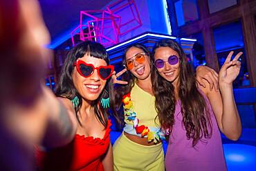 Friends in a nightclub taking a selfie with the phone at a night party on summer vacation in a pub