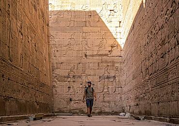 A young tourist visiting the beautiful temple of Edfu in the city of Edfu, Egypt. On the bank of the Nile river, geco-Roman construction, temple dedicated to Huros