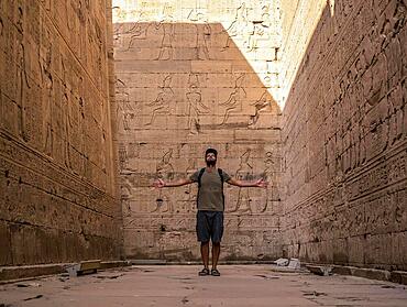 A young tourist visiting the beautiful temple of Edfu in the city of Edfu, Egypt. On the bank of the Nile river, geco-Roman construction, temple dedicated to Huros