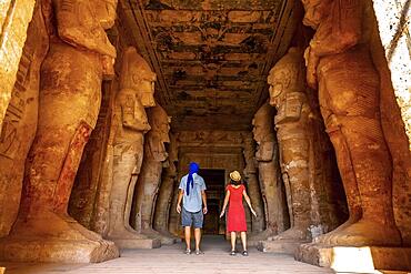 A tourist couple at the Abu Simbel Temple next to the sculptures, in southern Egypt in Nubia next to Lake Nasser. Temple of Pharaoh Ramses II, travel lifestyle