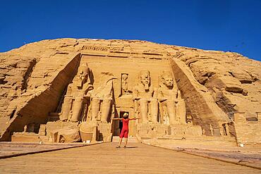 A European tourist in red dress at the Abu Simbel Temple in southern Egypt in Nubia next to Lake Nasser. Temple of Pharaoh Ramses II, travel lifestyle