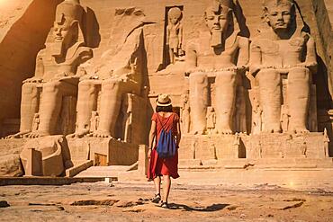 A young tourist in a red dress entering the Abu Simbel Temple in southern Egypt in Nubia next to Lake Nasser. Temple of Pharaoh Ramses II