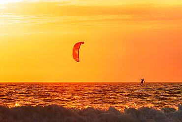 Foiling kiteboarding kitesurfing kiteboarder (kitesurfer) silhouette in the Atlantic ocean on sunset. Fonte da Telha beach, Costa da Caparica, Portugal, Europe