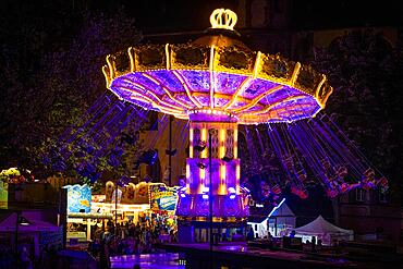 The colourful lights of the carousel at the Mainfest glow in the evening. The Mainfest on the Mainkai, Fahrtor and Roemerberg is one of Frankfurt's oldest public festivals. The official opening takes place in 2023 on 04 August at 6 p.m. at the Gerechtigkeitsbrunnen on Roemerberg. The festival ends with a big fireworks display over the Main on Monday, 07.08.2023., Mainufer, Frankfurt am Main, Hesse, Germany, Europe