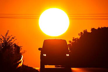 A car driving along a country road near Frankfurt am Main at sunrise, Frankfurt am Main, Hesse, Germany, Europe