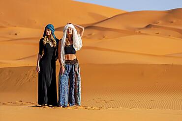 A beautiful model poses against the sand dunes in the great Sahara desert in Morocco