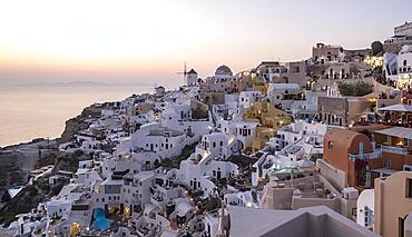 Cliff-side houses, villas and windmill in the village of Oia, Ia, as seen from the Kasteli Castle, Santorini, Greece, Europe