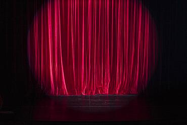 Empty stage with light spot on red curtain