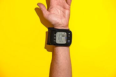 Blood pressure monitor on a man's trading joint against a yellow background, top view