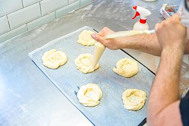 Baker of bakery in the workshop workshop of artisan bakery preparing the buns before baking