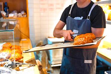 Bakery baker in workshop workshop of artisan bakery and shop placing croissant and neapolitan