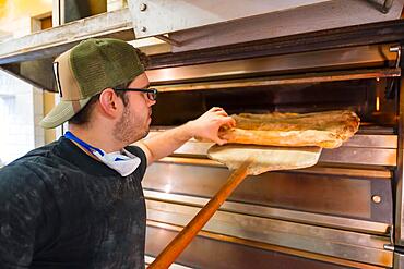 Baker of bakery in the workshop artisan workshop baking loaves in the oven