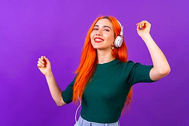 Redhead woman in studio photography dancing on a purple background