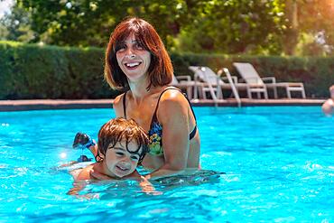 Mother and son in the pool on summer vacation, learning to swim