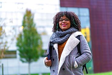 Portrait of black ethnic girl in college in autumn with college in background, back to school