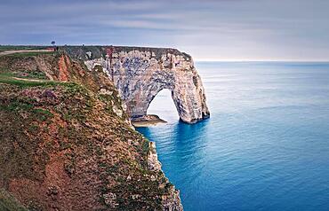 Sightseeing view to the Porte d'Aval natural arch cliff washed by Atlantic ocean waters at Etretat, Normandy, France. Beautiful coastline scenery with famous Falaise d'Aval