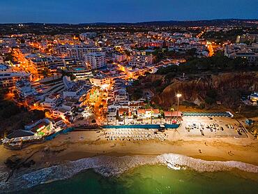 The beach of Olhos de Agua, a former fishing village in the Portuguese Algarve in the district of Faro, near the town of Albufeira, is illuminated in the evening and at night by huge floodlight masts so that beachgoers can still swim in the Atlantic after sunset. (Aerial photo taken with a drone), Algarve, Olhos de Agua, Faro, Portugal, Europe