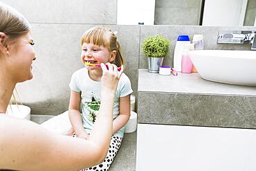 Mother brushing teeth daughter