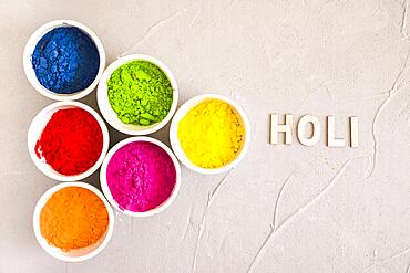 Holi text near different type color powder concrete background