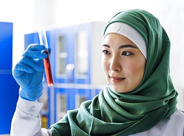 Side view female scientist with hijab holding substance