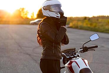 Side view woman taking off her helmet motorcycle