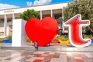 Portrait of a child in the I Love Tirana sculpture at Skanderbeg Square in Tirana reflected. Albania