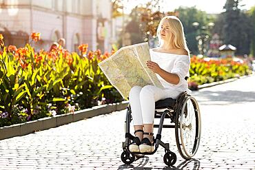 Woman wheelchair looking map outdoors