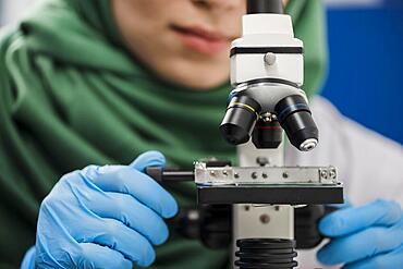 Female scientist with hijab working lab with microscope