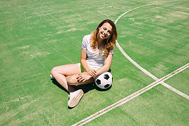 Happy teenager with ball football pitch