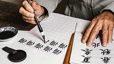 High angle person writing chinese symbols white paper