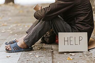 Side view homeless man street with cup help sign