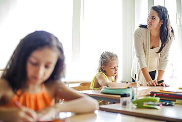 Female teacher leaning upon table looking away