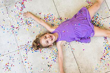 Overhead view happy cute girl lying with confetti floor